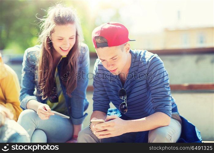 technology, internet and people concept - happy teenage friends with smartphones outdoors. happy teenage friends with smartphones outdoors. happy teenage friends with smartphones outdoors