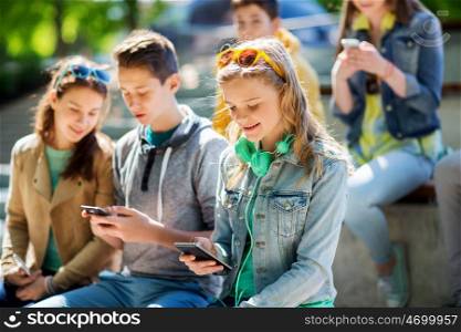 technology, internet and people concept - happy teenage girl with smartphone and headphones outdoors