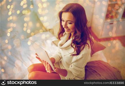 technology, internet and people concept - happy young woman lying in bed with tablet pc computer at home bedroom. happy young woman with tablet pc in bed at home