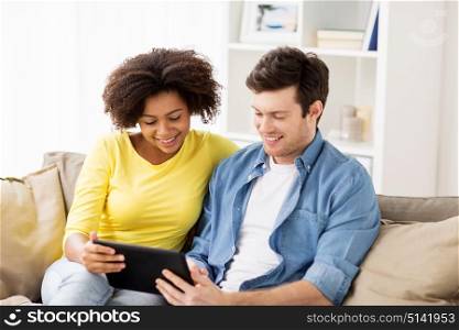 technology, internet and people concept - smiling happy couple with tablet pc computer at home. smiling happy couple with tablet pc at home