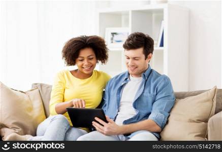 technology, internet and people concept - smiling happy couple with tablet pc computer at home. smiling happy couple with tablet pc at home