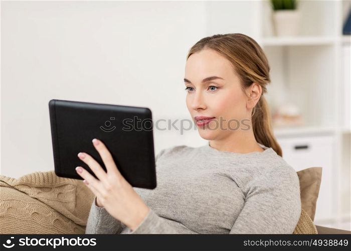 technology, internet and people concept - smiling woman sitting on couch with tablet pc computer at home. smiling woman with tablet pc at home