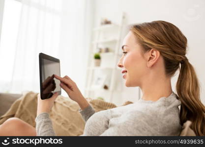 technology, internet and people concept - smiling woman sitting on couch with tablet pc computer at home. smiling woman with tablet pc at home