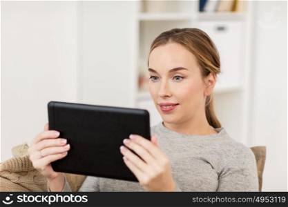 technology, internet and people concept - smiling woman sitting on couch with tablet pc computer at home. smiling woman with tablet pc at home