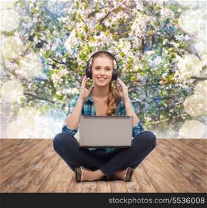 technology, internet and people concept - smiling young woman in casual clothes sitiing on floor with laptop computer and headphones