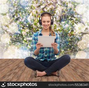 technology, internet and people concept - smiling young woman in casual clothes sitiing on floor with tablet pc computer and headphones