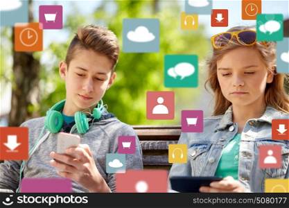 technology, internet and people concept - teenage boy with smartphone and headphones and girl with tablet pc computer outdoors over virtual icons. teenage friends with gadgets outdoors