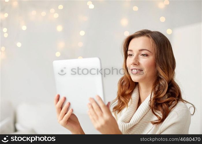 technology, internet, christmas and people concept - happy young woman with tablet pc computer at home