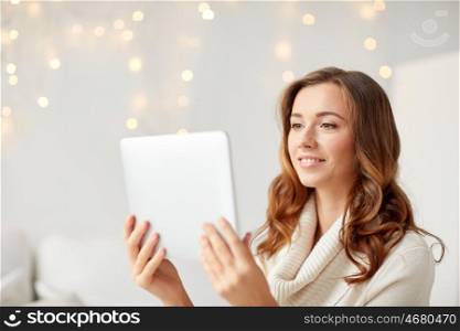 technology, internet, christmas and people concept - happy young woman with tablet pc computer at home