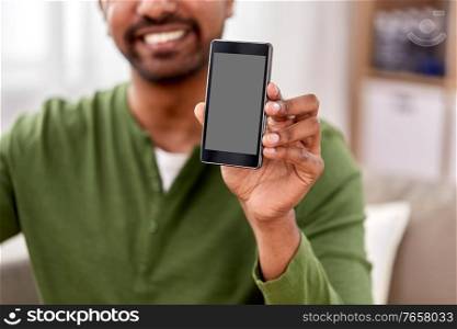 technology, internet, communication and people concept - close up of happy smiling indian man showing smartphone at home. close up of smiling man showing smartphone at home