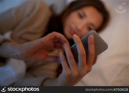 technology, internet, communication and people concept - close up of woman texting on smartphone in bed at home at night