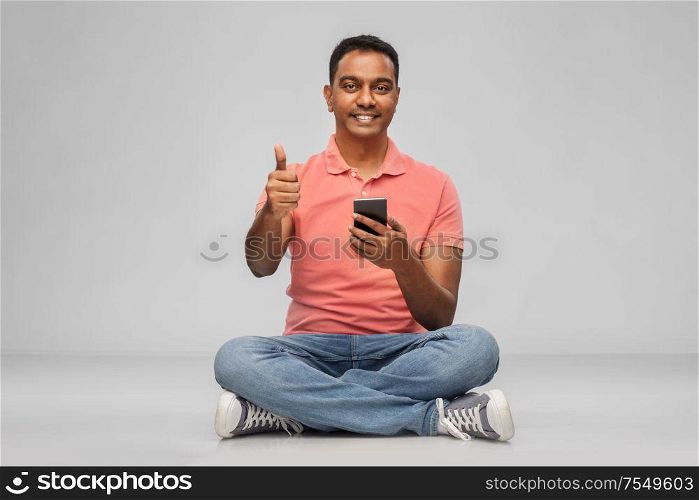technology, internet, communication and people concept - happy indian man with smartphone showing thumbs up over grey background. happy indian man with smartphone showing thumbs up