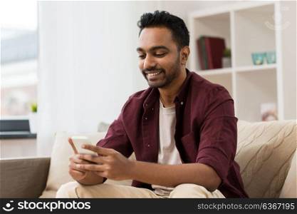 technology, internet, communication and people concept - happy smiling man messaging on smartphone at home. happy man with smartphone at home