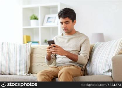 technology, internet, communication and people concept - man texting on smartphone at home. man with smartphone at home