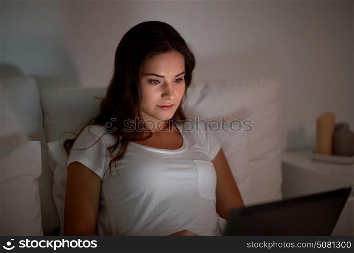 technology, internet, communication and people concept - young woman with laptop computer in bed at home bedroom at night. young woman with laptop in bed at home bedroom