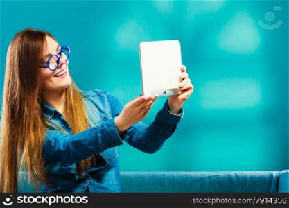 Technology internet modern lifestyle concept. girl using digital tablet taking picture of herself. Selfie style. Woman with e-book reader touchpad pc on couch, blue color
