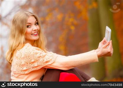 Technology internet modern lifestyle concept. Woman in autumn park using tablet computer reading. Girl with e-book reader touchpad pc outdoor