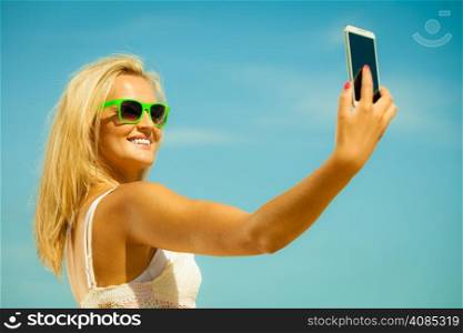 Technology internet tourism vacation concept - happy woman teen girl taking self picture with smartphone camera on beach