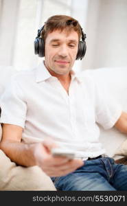 technology, leisure and lifestyle concept - happy man with headphones listening to music at home