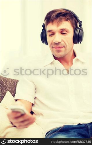 technology, leisure and lifestyle concept - happy man with headphones listening to music at home