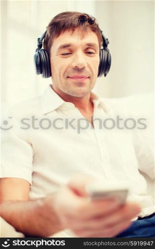 technology, leisure and lifestyle concept - happy man with headphones listening to music at home