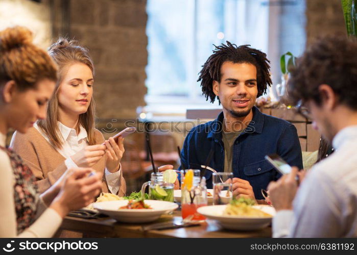 technology, leisure and people concept - friends with smartphones at bar or restaurant. friends with smartphones at bar or restaurant