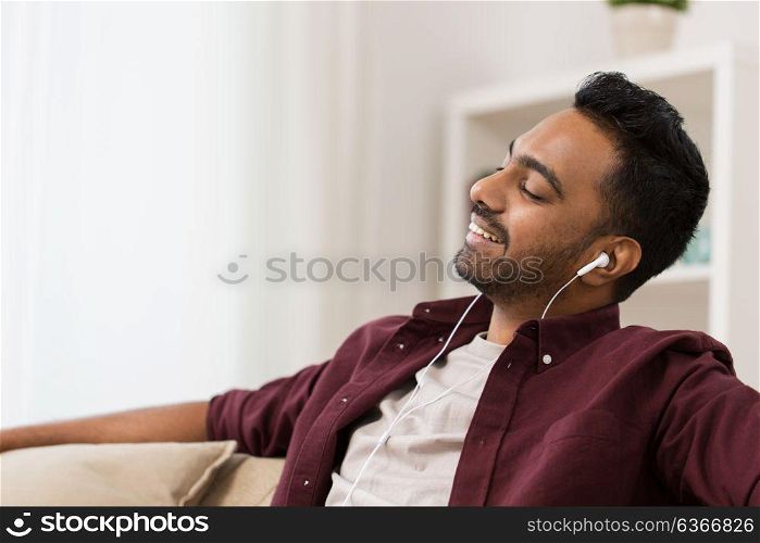 technology, leisure and people concept - happy man in earphones listening to music at home. happy man in earphones listening to music at home