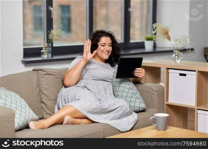 technology, leisure and people concept - happy smiling woman with tablet pc computer having video chat and waving hand at home. woman with tablet pc having video chat at home