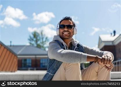 technology, leisure and people concept - indian man in headphones listening to music on roof top. man in headphones listening to music on roof top