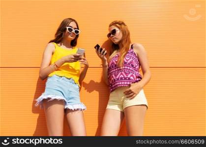 technology, leisure and people concept - teenage girls in summer clothes with smartphones outdoors. teenage girls with smartphones in summer outdoors