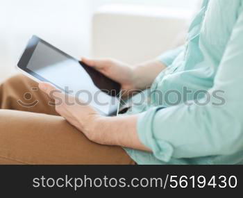 technology, leisure, lifestyle and advertisement concept - close up of man working with tablet pc computer sitting on sofa at home