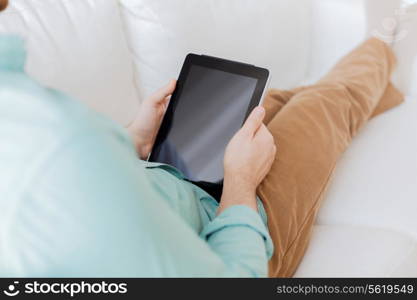 technology, leisure, lifestyle and advertisement concept - close up of man working with tablet pc computer sitting on sofa at home