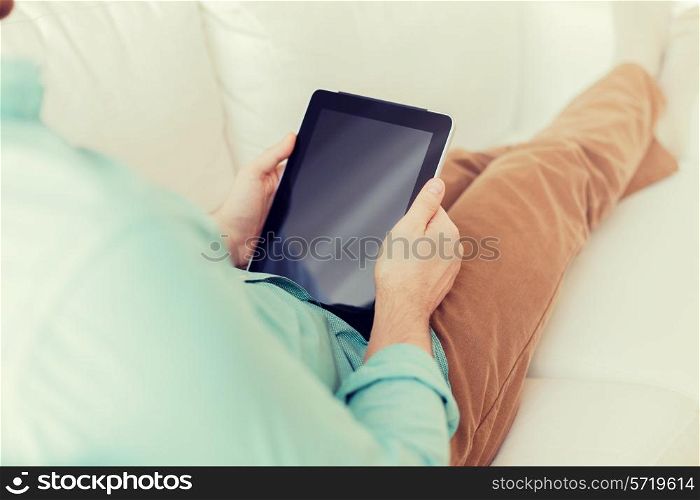 technology, leisure, lifestyle and advertisement concept - close up of man working with tablet pc computer sitting on sofa at home