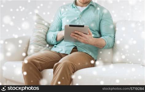 technology, leisure, people and distance learning concept - close up of man working with tablet pc computer sitting on sofa at home