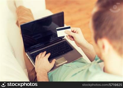 technology, leisure, shopping, banking and lifestyle concept - close up of man with laptop computer and credit card at home