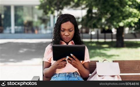 technology, lifestyle and people concept - african american woman with tablet pc computer in city. african american woman with tablet pc in city