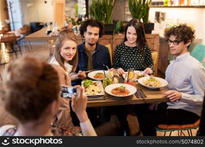 technology, lifestyle and people concept - happy friends with smartphone having dinner and photographing at restaurant. friends with smartphone fotographing at restaurant