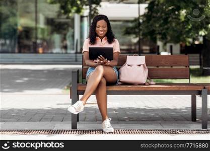 technology, lifestyle and people concept - happy smiling african american woman with tablet pc computer in city. african american woman with tablet pc in city