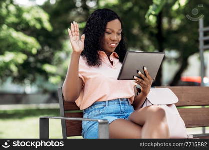 technology, lifestyle and people concept - happy smiling african american woman with tablet pc computer having video call in city. african woman with tablet pc having video call