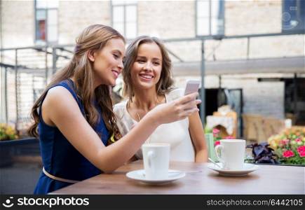 technology, lifestyle and people concept - happy young women with smartphone drinking coffee at cafe outdoors. young women with smartphone and coffee at cafe