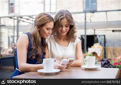 technology, lifestyle and people concept - happy young women with smartphones drinking coffee at cafe outdoors. young women with smartphones and coffee at cafe. young women with smartphones and coffee at cafe