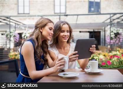 technology, lifestyle and people concept - happy young women with tablet pc computer drinking coffee at cafe outdoors. young women with tablet pc drinking coffee at cafe