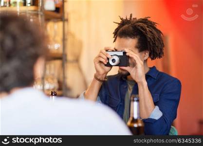 technology, lifestyle and people concept - man with camera photographing friend at bar. man with camera photographing friend at bar