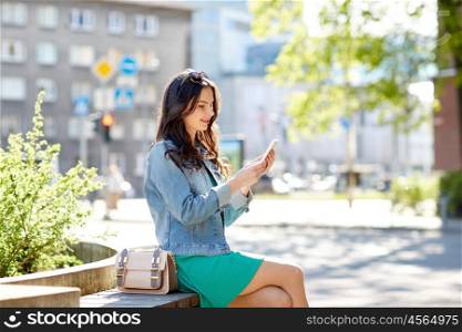 technology, lifestyle and people concept - smiling young woman or teenage girl with smartphone texting on city street