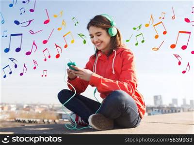 technology, lifestyle and people concept - smiling young woman or teenage girl with smartphone and headphones listening to music outdoors over colorful musical notes background