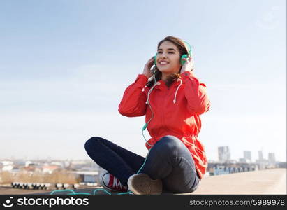 technology, lifestyle and people concept - smiling young woman or teenage girl in headphones listening to music outdoors