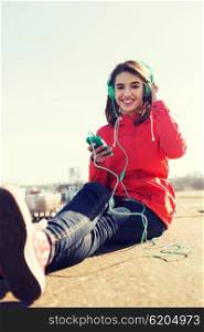 technology, lifestyle and people concept - smiling young woman or teenage girl with smartphone and headphones listening to music outdoors