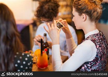 technology, lifestyle and people concept - woman with smartphone taking picture of food at restaurant. woman with smartphone oicturing food at restaurant