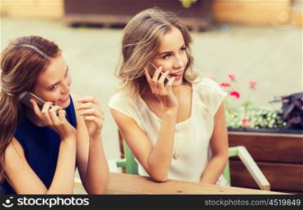 technology, lifestyle, communication and people concept - happy young women or teenage girls calling on smartphones at cafe outdoors
