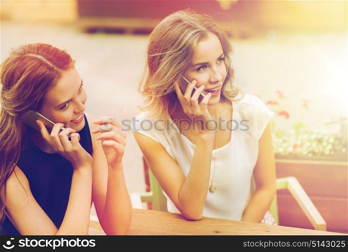technology, lifestyle, communication and people concept - happy young women or teenage girls calling on smartphones at cafe outdoors. happy young women with smartphones at outdoor cafe